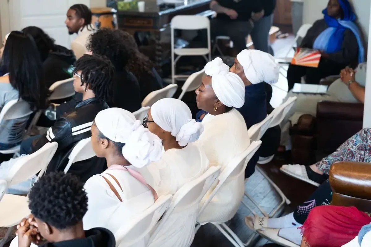 The congregation, many in white head coverings, listening to a teaching.