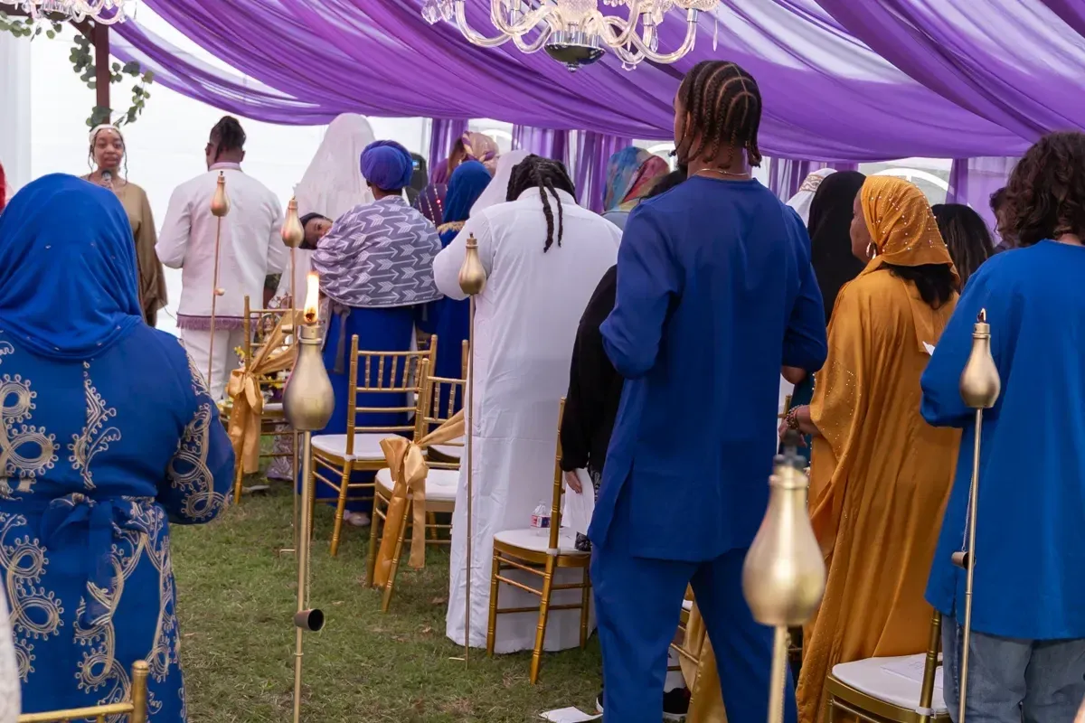 The congregation gathered beneath a purple canopy for worship outdoors.