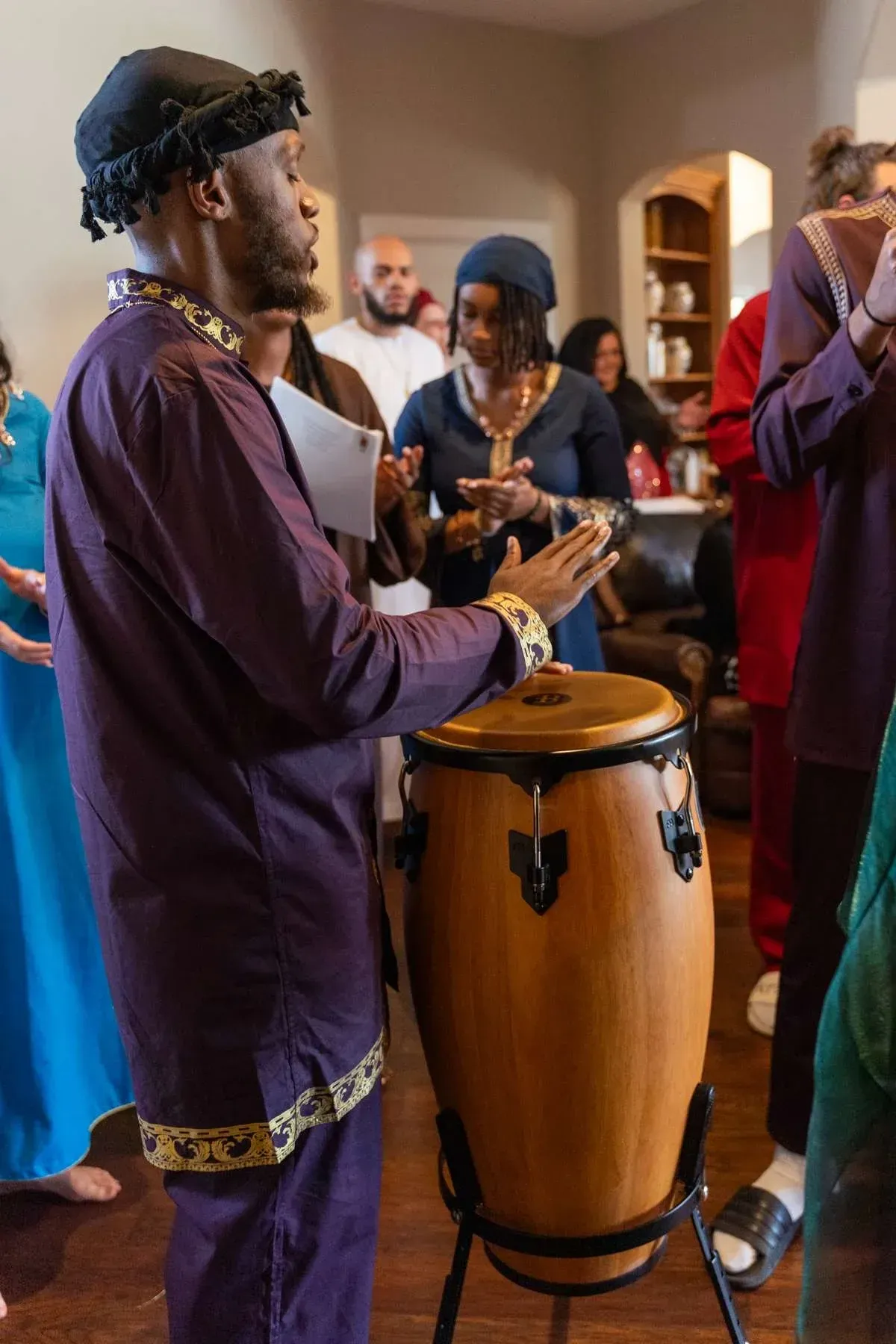 A drummer in robes leads praise during a gathering.