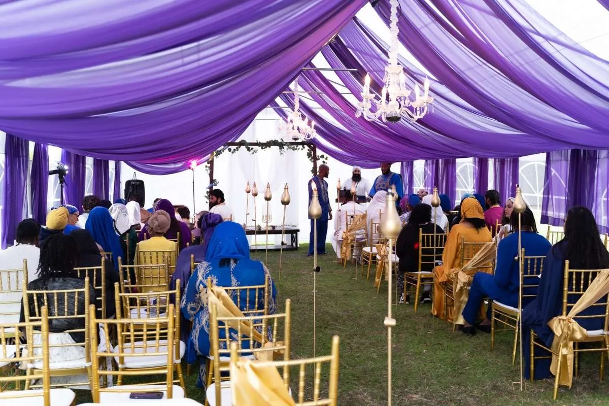 The mishfaha seated for the feast beneath a purple canopy with gold chairs.
