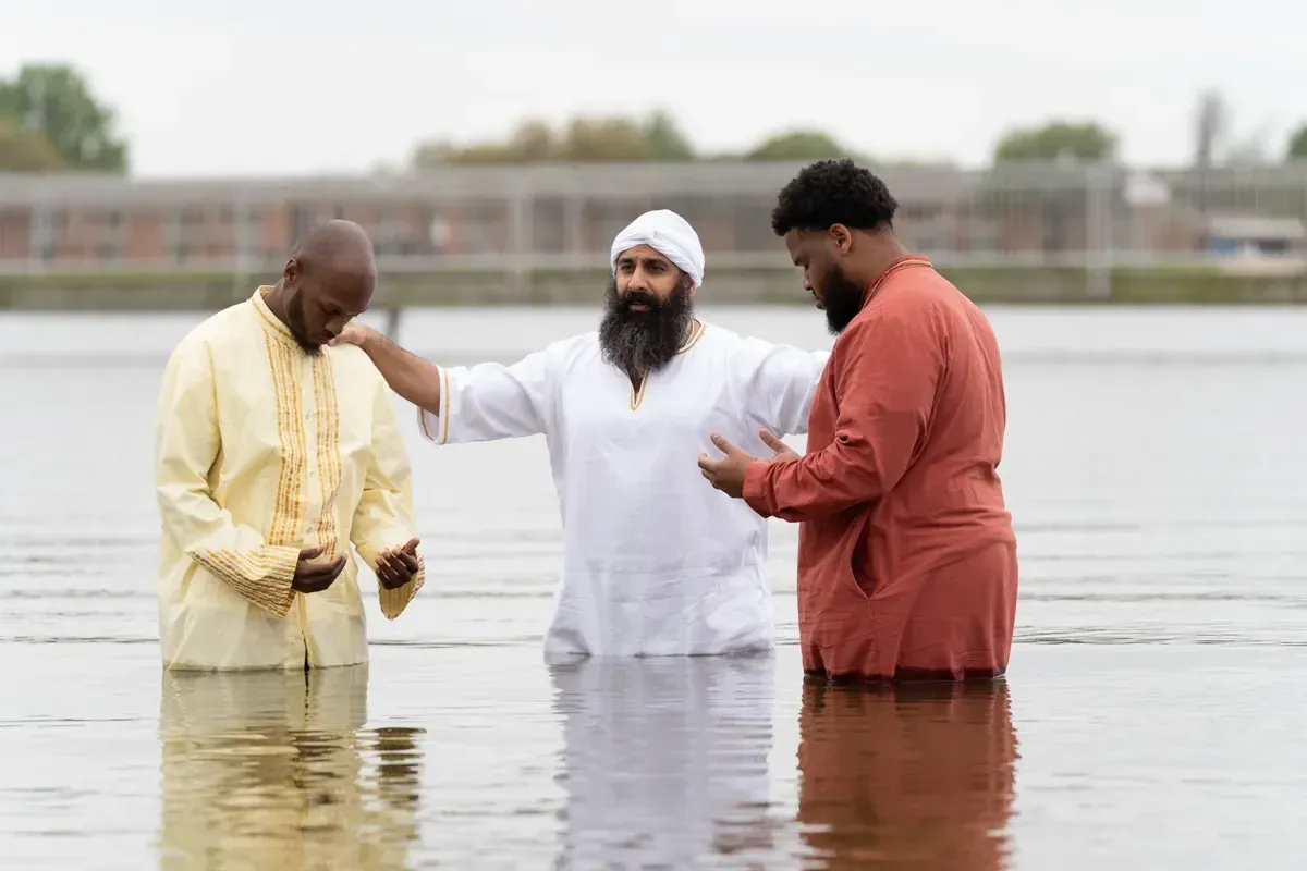Rab Kahana Yamin Ben-EL prays over two men standing in the water during immersions.