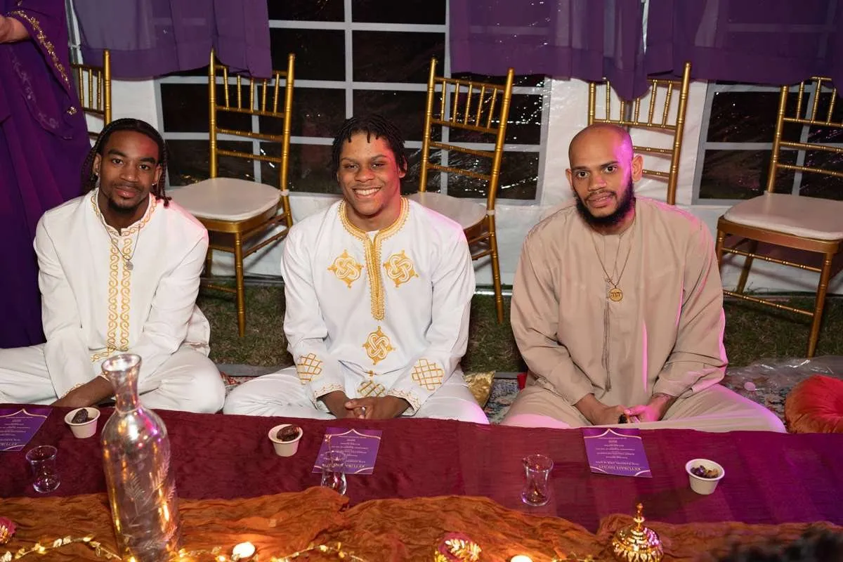 Three leaders in festive robes seated at a candlelit feast table.
