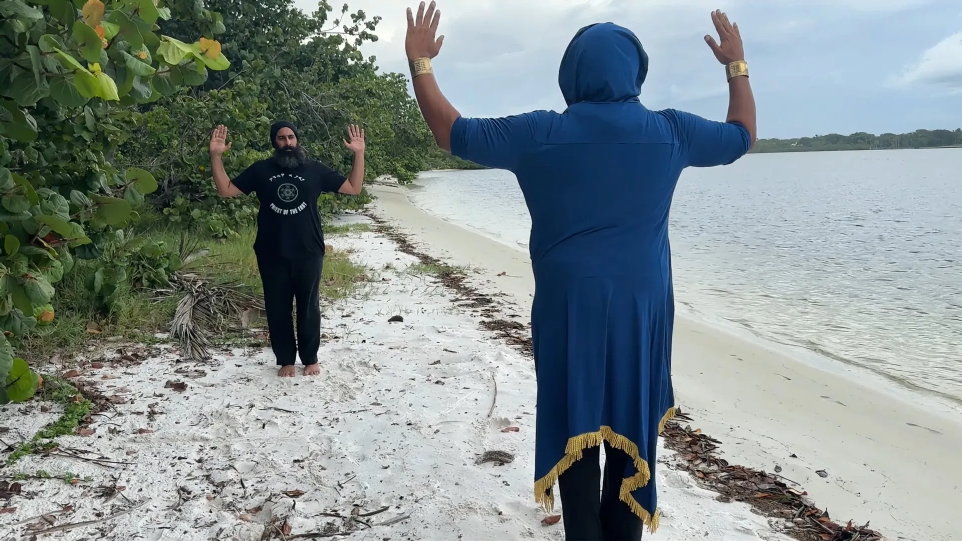 Two believers pray with raised hands at the water’s edge.