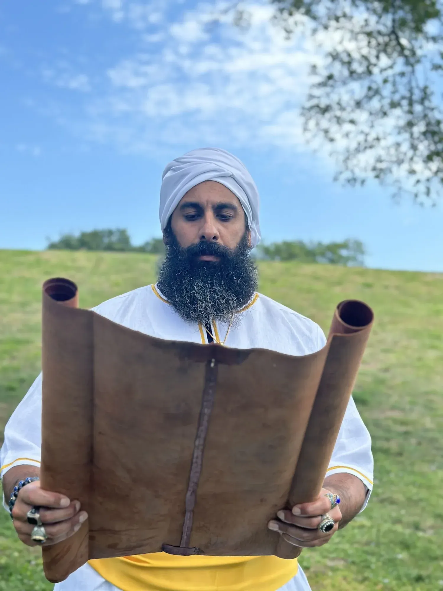 Rab Kahana Yamin Ben-EL holding an open scroll outdoors.