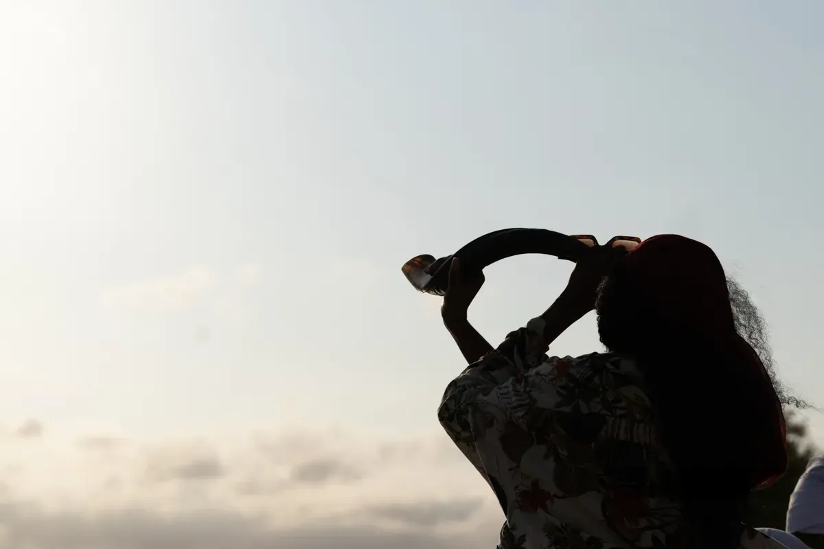 A woman sounds the shofar towards the sky.