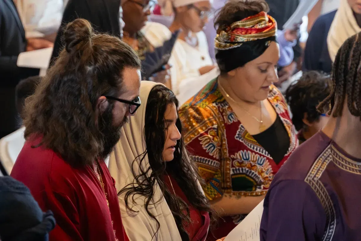 Members in colourful garments worshipping together indoors.
